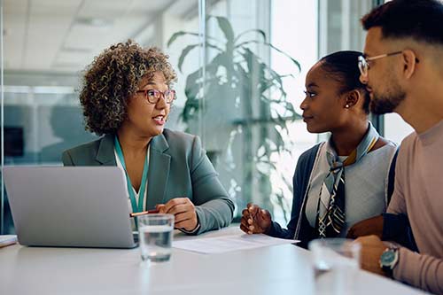 Bank Manager talking to young couple during meeting in office.